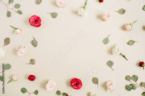 Flowers frame made of beige and red roses, eucalyptus leaf on pale pastel beige background. Flat lay, top view. Floral wreath frame background.