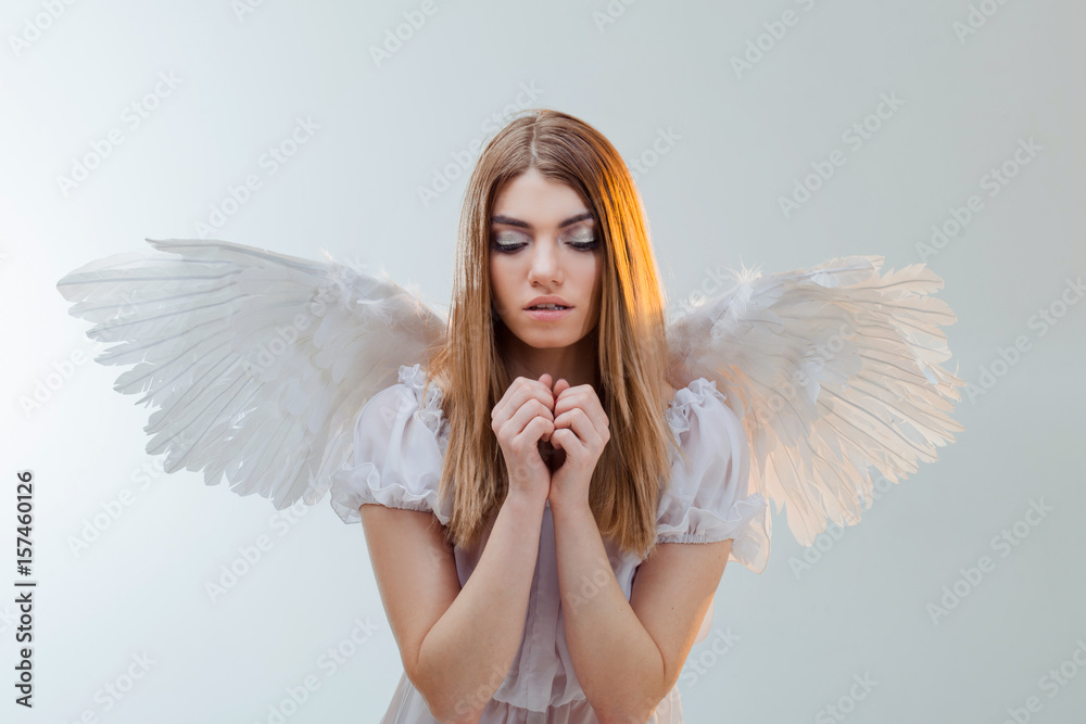 An angel from heaven holding something on the palms. Young, wonderful blonde girl in the image of an angel with white wings. An angel from heaven holding something on the palms. Young, wonderful blonde girl in the image of an angel with white wings.