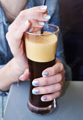 woman with beautiful manicure holds a cold coffee - blue and white polish with glitter