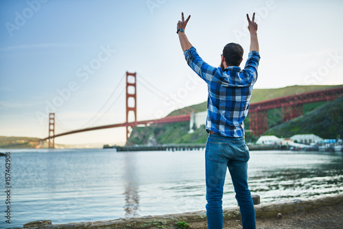 cool guy cheering and making peace sign in front of golden gate bridge in san francisco