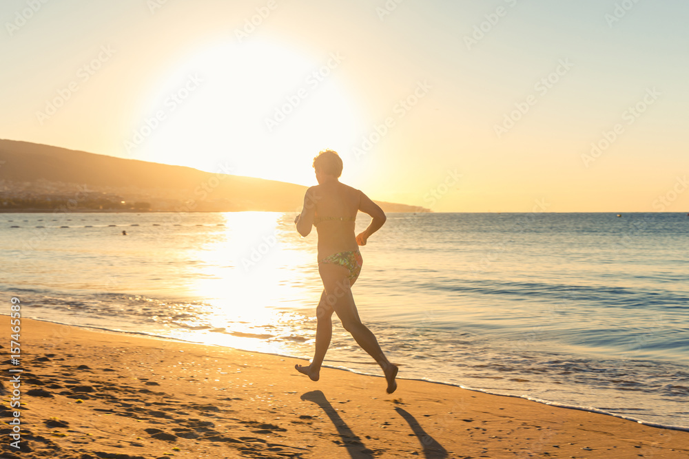 An eldery woman jogging outdoors on morning beach