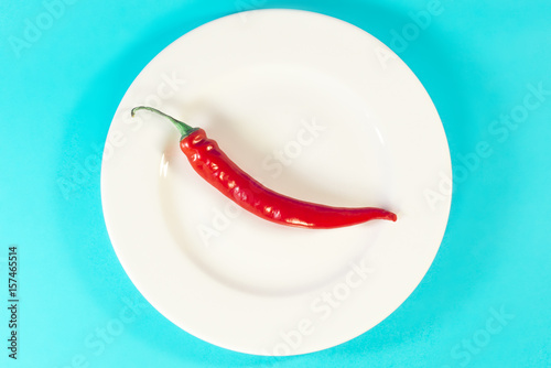 Papryka czerwona papryczka chili na białym talerzu turkusowe niebieskie tło photo