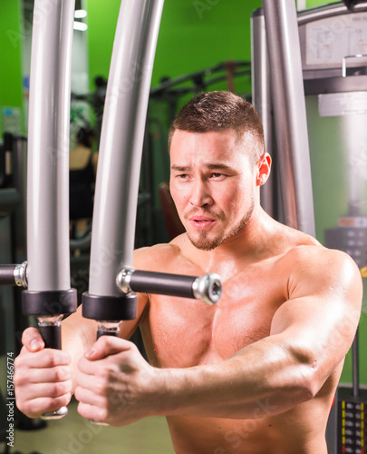Strong muscular handsome man exercising at the gym