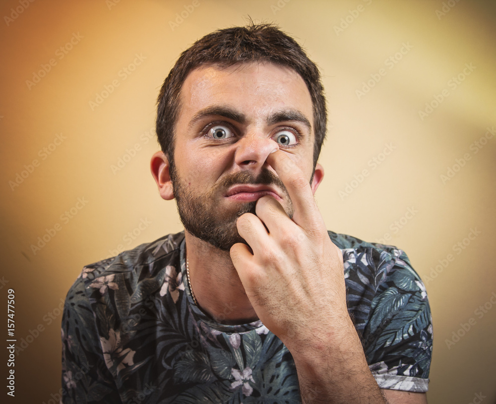 Young man with finger in his nose, picking the nostrils Stock Photo