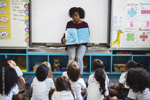 Kindergarten students sitting on the floor listening to story telling photo