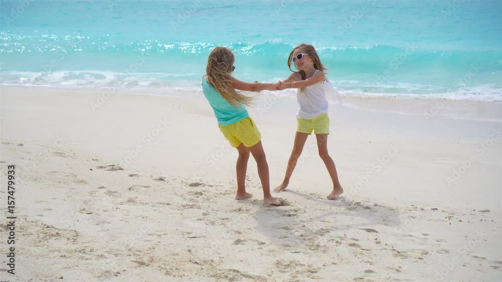 Adorable little girls have fun together on white tropical beach Adorable little girls have fun together on white tropical beach