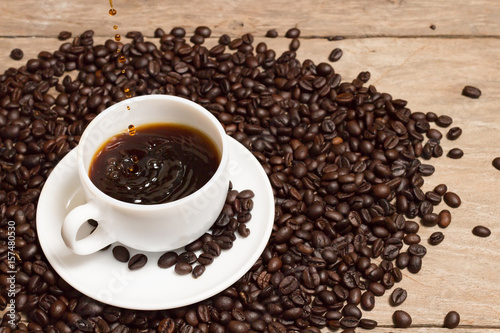 pouring coffee with rosted coffee beans in white cup