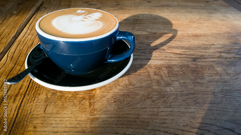 Obraz premium Hot mocha coffee or cappuccino in the blue cup with luxury pattern on the wooden table