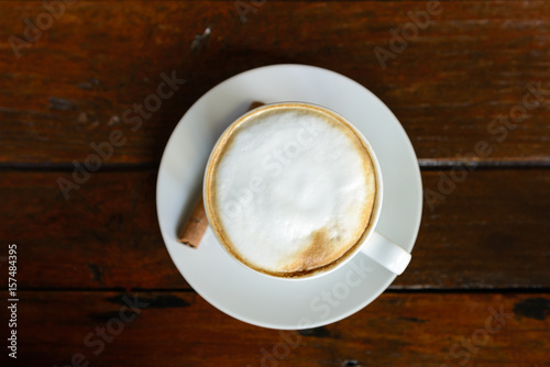 Top view of hot coffee cappuccino cup with milk foam on wood table