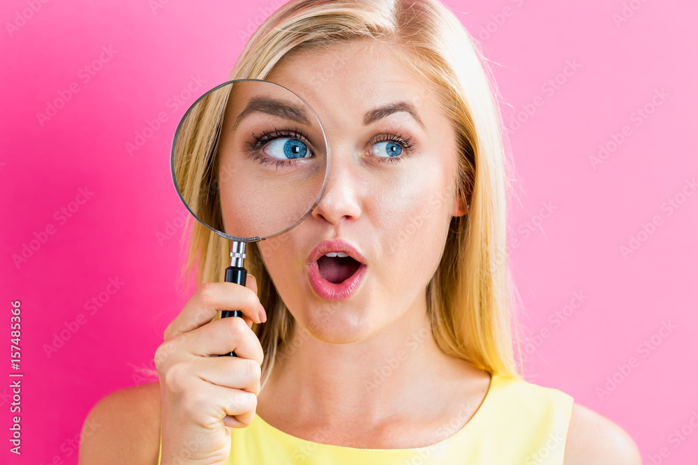 Young woman looking through a magnifying glass Young woman looking through a magnifying glass