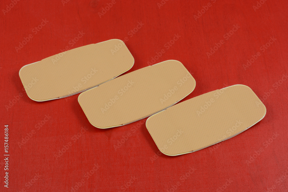 Three large first aid adhesive bandages on red background Three large first aid adhesive bandages on red background