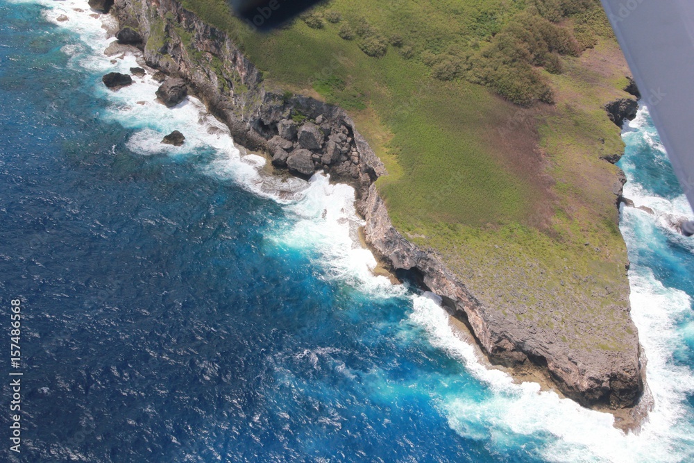 Obraz premium Sharp cliff drops and waves Huge waves slap against sharp rocks below steep cliff drops