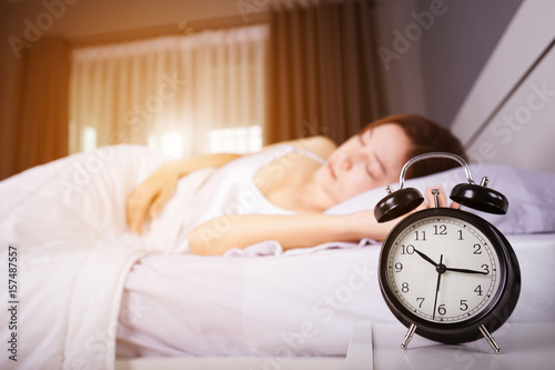 clock show 10 am. and woman sleeping on bed with sunlight in morning