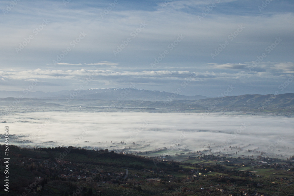 An aerial view of a valley half filled by fog