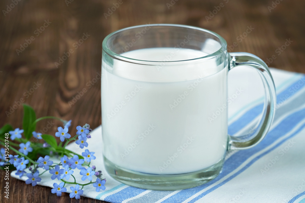 Milk in a glass Cup on a wooden table. Blue flowers. Milk in a glass Cup on a wooden table. Blue flowers.