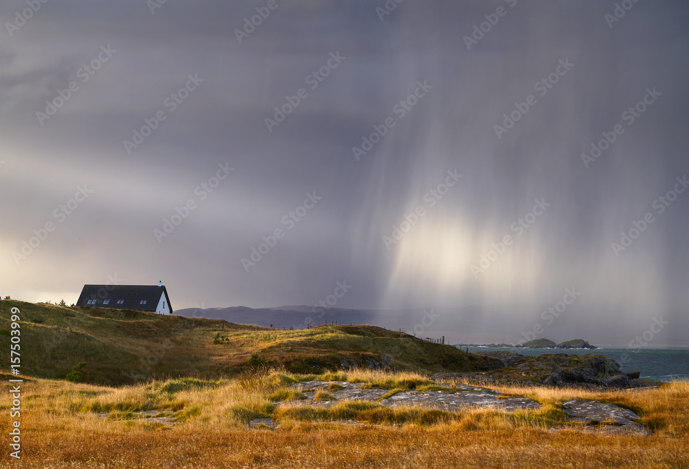 A heavy rain shower over a croft at Loch Ewe, Scottish Highlands, Scotland, UK.