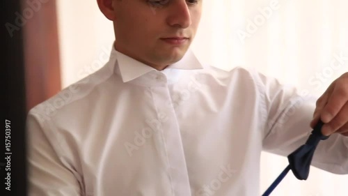 The courageous groom dresses his wedding suit. He holds a bouquet in his hands. Wedding day. Spring. photo