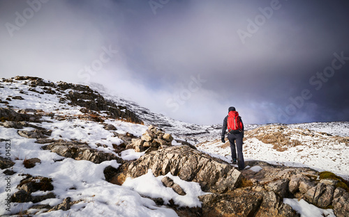 A hiker walking along the mountain path route on Beinn Eighe, Scottish Highlands, Scotland, UK.