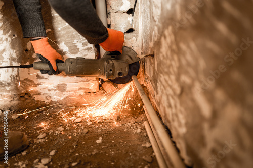 Worker cuts a metal pipe with sparks