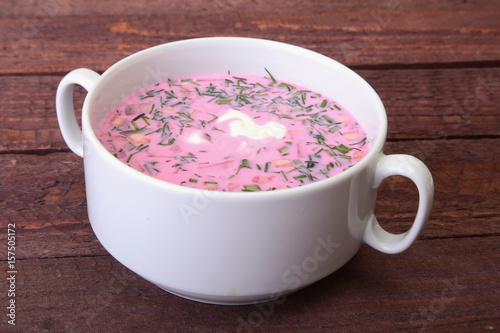 Popular spring cold soup okroshka with yoghurt. Okroshka in a bowl on wooden table. Selective focus