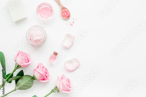 body treatment with rose flowers and cosmetic set white desk background top view space for text
