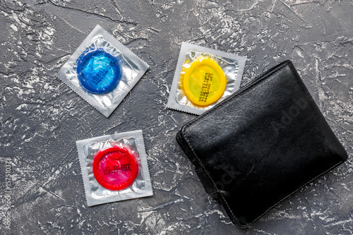 condoms and wallet for male contraception and birth control dark background top view