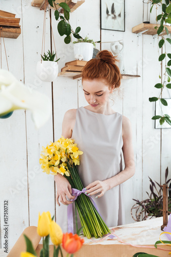 Redhead florist bandaging flowers with violet ribber photo