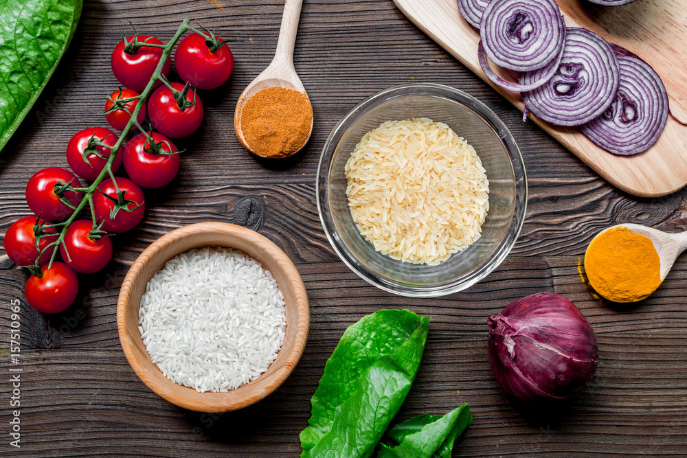 paella ingredients with rice, salt, spices and tomatoes on wooden table background top view