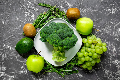 healthy food with green vegetables, fruits for dinner on dark table background top view photo