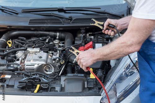 Car mechanic using car battery jumper cable © thodonal