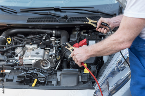 Car mechanic using car battery jumper cable