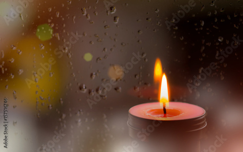 Vintage image of Light of Pink Candle in the front at window with blurred rain drops and low light nature background