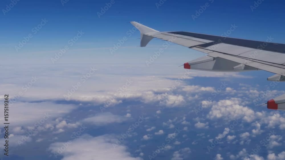 View from a plane window: a plane wing over clouds and blue sky. Traveling by air. Airplane flying above earth at 10000 m -50 °C (-58.0 °F). Ice and dust on airplane window. 4K footage at 60fps. View from a plane window: a plane wing over clouds and blue sky. Traveling by air. Airplane flying above earth at 10000 m -50 °C (-58.0 °F). Ice and dust on airplane window. 4K footage at 60fps.