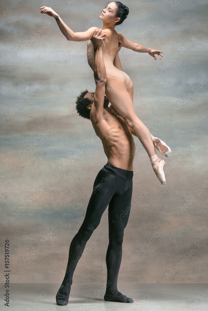 Obraz premium Couple of ballet dancers posing over gray background