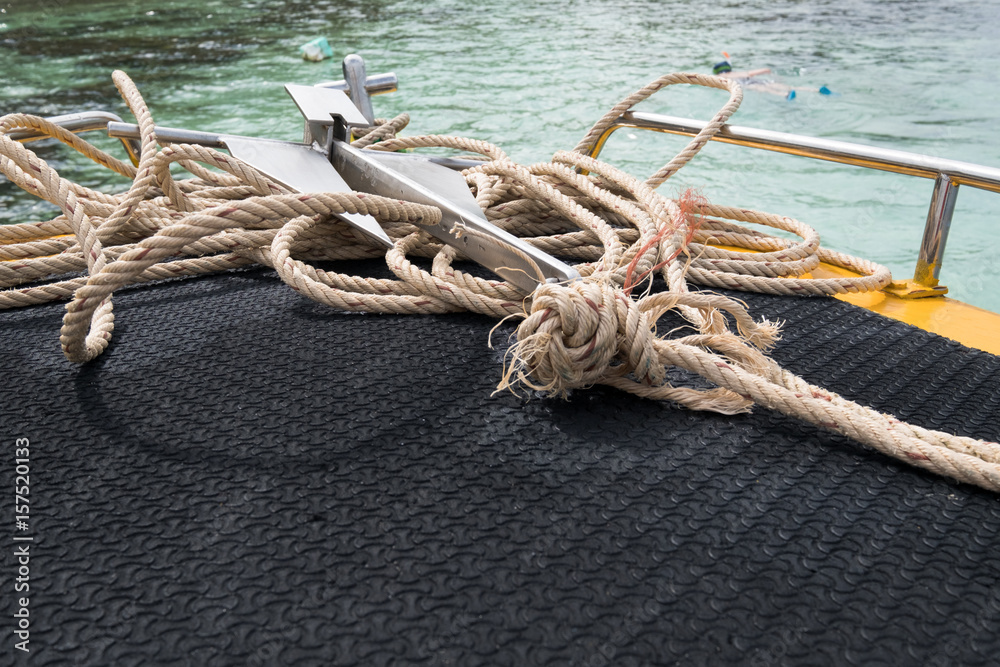 Focus on a small anchor with rope on the boat