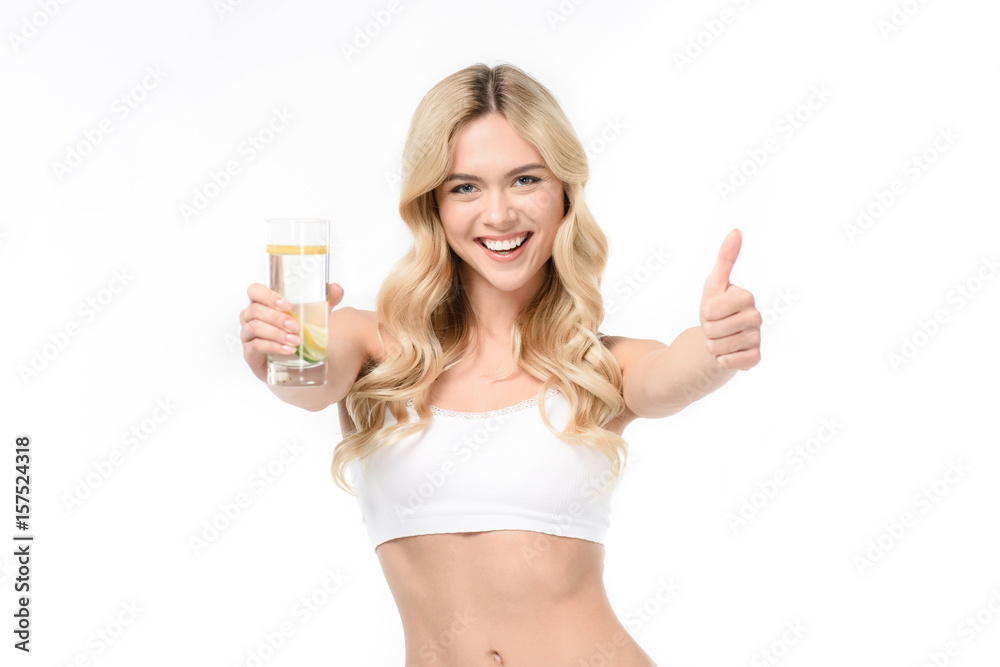 woman in white underwear holding glass of water with lemon and showing thumb up woman in white underwear holding glass of water with lemon and showing thumb up