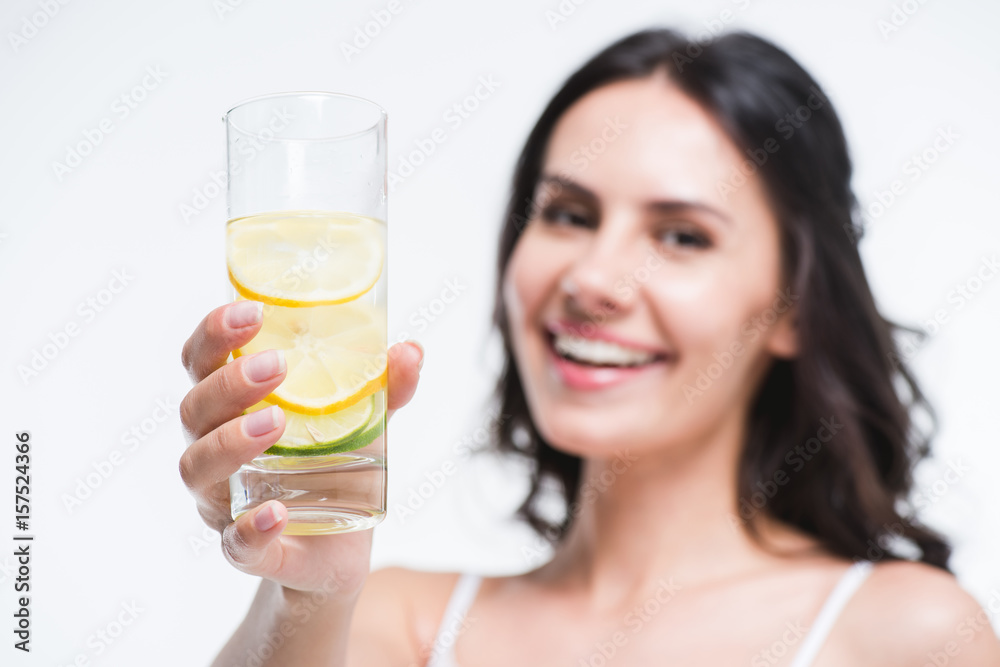 smiling woman showing glass of water with lemon isolated on white smiling woman showing glass of water with lemon isolated on white