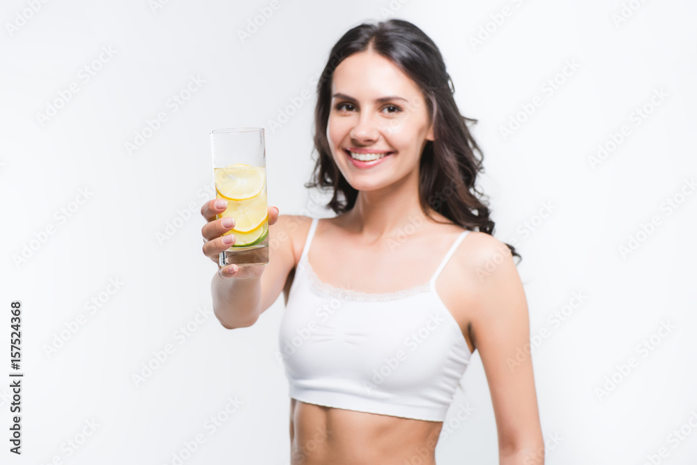 smiling woman showing glass of water with lemon isolated on white smiling woman showing glass of water with lemon isolated on white