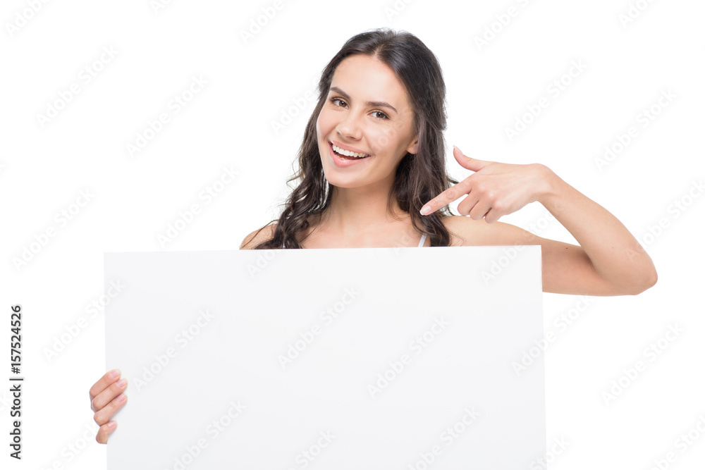 Smiling young woman holding blank card and pointing with finger at copy space Smiling young woman holding blank card and pointing with finger at copy space