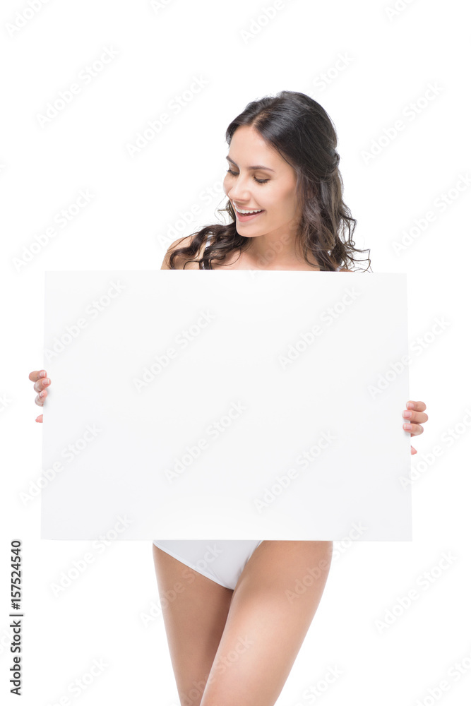 Smiling young woman in underwear holding blank card and looking at copy space Smiling young woman in underwear holding blank card and looking at copy space