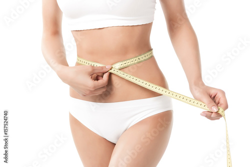 cropped view of woman with perfect slim body measuring her waistline isolated on white