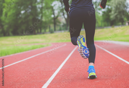 Athletic woman running on track back view, healthy lifestyle