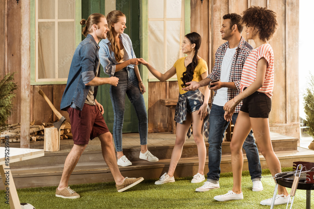 Obraz premium multiethnic group of cheerful friends gesturing and having fun together