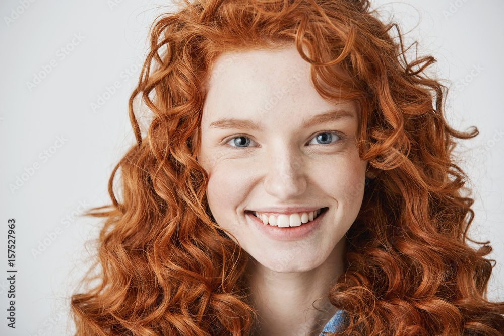 Close up of redhead beautiful girl with freckles smiling looking at camera over white background. Close up of redhead beautiful girl with freckles smiling looking at camera over white background.