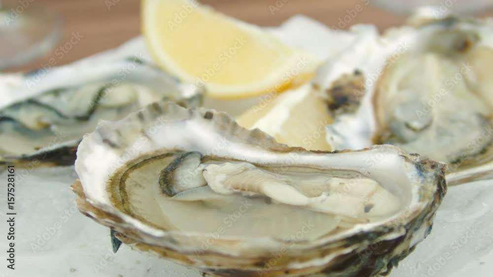 Super close-up of fresh oysters on a white plate with ice. The circular movement of the camera Super close-up of fresh oysters on a white plate with ice. The circular movement of the camera