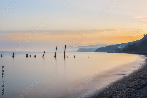 Sea landscape, the sea at sunset, twilight, long exposure. Calm sea. Beautiful beach. Silhouettes of hills on the shore in the haze in the distance. 