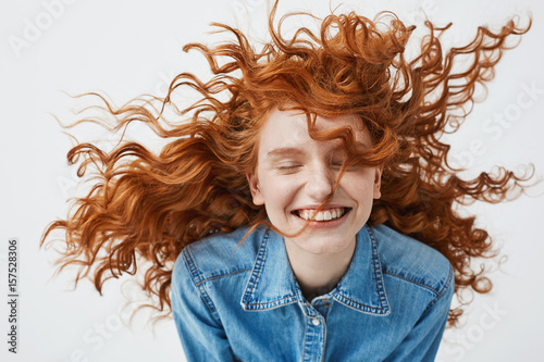 Photography Attractive cheerful redhead girl with flying curly hair smiling laughing with closed eyes over white background