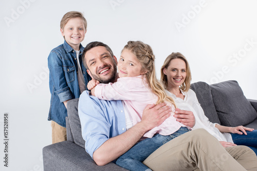 caucasian family looking at camera while sitting on sofa together isolated on white