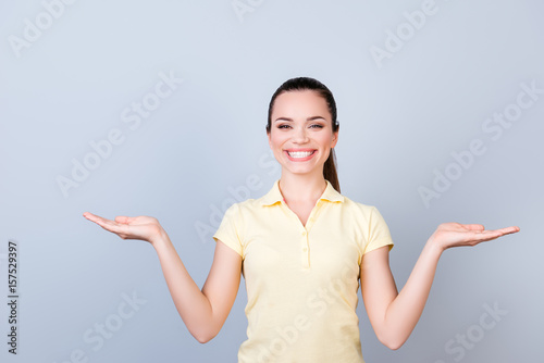 Cuadro en lienzo Cheerful charming girl in casual tshirt on pure background is gesturing with han