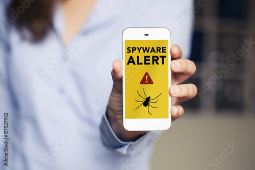 Spyware alert in a mobile phone held by hand.
